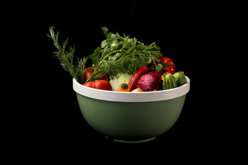 Raw vegetables in a bowl on a black background. Side view