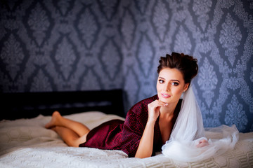 Portrait of beautiful bride posing on bed at wedding morning.