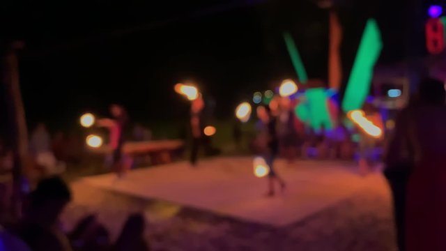 defocused fire performance. blurred people performers spinning burning flames at night at festival or celebration event. professional acrobat dancer puts fire show. bokeh carnival in thailand