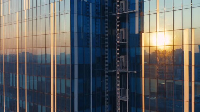 Aerial elevator shot of the modern glass skyscraper exterior with sunshine and reflection on the windows