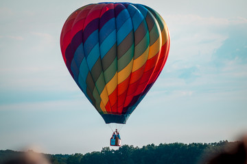 Obraz premium Rainbow hot air balloon flying through the sky at sunset
