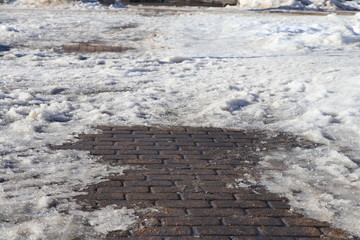 Snow and concrete plates  on the pedestrian path. Thaw after winter in the city.