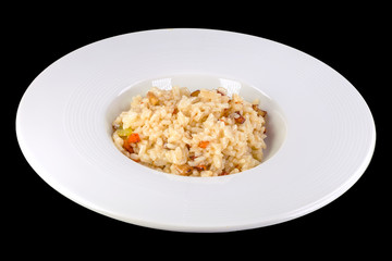 Tasty risotto with vegetables in a white plate, isolated on black background