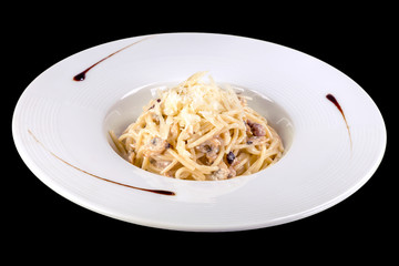 Tasty spaghetti with seafood and cheese in a white plate, isolated on black background