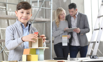 Happy children playing building a house with construction models. His family chooses how to...