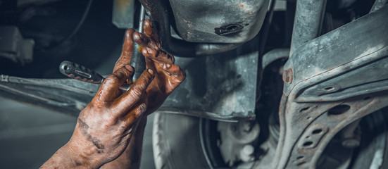 A car mechanic repairs a car at a car repair shop with a turnkey. close-up on hands
