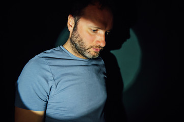 Obraz premium Portrait of young man on black background with hard light. .