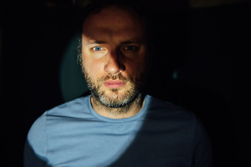 Portrait of young man on black background with hard light. .