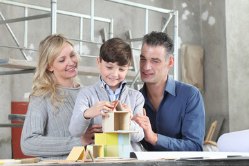 Happy children and his family playing building a house with construction models at interior site. House buy and building goal concept