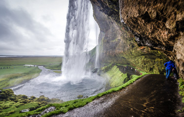 Tourist on Seljalandsfoss waterfall on Seljalands River that has its origin in Eyjafjallajokull volcano, Iceland