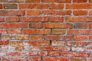 Naklejka premium Red brick pattern. Old brick wall with cracks and scratches. Horizontal background of wide brick wall. Disturbed wall with broken brick texture. Vintage house facade.