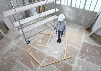 New building residential house purchase apartment concept. Child plays building the frame of a wooden house with door, window, wall and roof. Inside of interior construction site