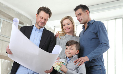 Architect showing house design plans to a family with child. Meeting at interior construction site to talk about house appearance, interior decoration, home layout and wall colors