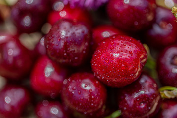 Macro image of red cherries and green leaves. Natural background of summer sweet fruits.