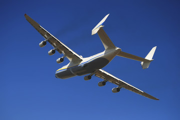 Mriya airplane in the blue sky with a smoke coming from the engines. An225. Antonov