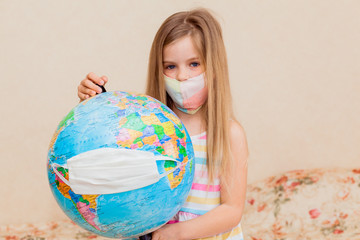 little girl in a medical mask holds a globe in her hands, wrapped in a medical mask. Little girl...