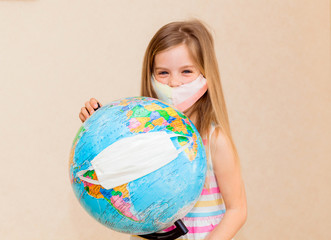 little girl in a medical mask holds a globe in her hands, wrapped in a medical mask. Little girl...
