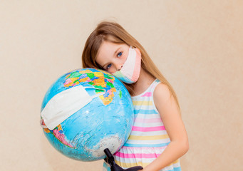 little girl in a medical mask holds a globe in her hands, wrapped in a medical mask. Little girl...