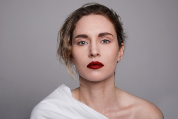 Headshot of young woman with red lips wearing white clothing. Close-up portrait. Space for text.