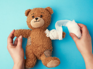funny vintage brown curly teddy bear with rewound paw with white gauze bandage