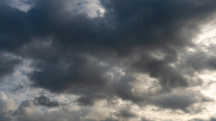 Obraz premium A cluster of light and fluffy clouds interspersed with dark gray clouds. Before the rain and the thunderstorm.
