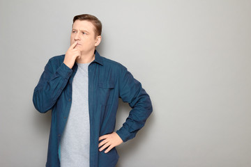 Portrait of thoughtful focused man touching lips with finger