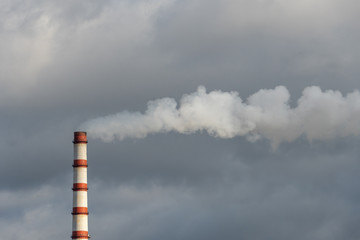 the smoke from the power plant chimney. Environmental pollution. non-renewable energy sources.  Large chimney against a background of grey clouds. Environmental disaster.