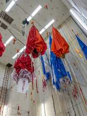 Parachutes hanging from ceiling after being checked and waiting for folding and packing prior to...