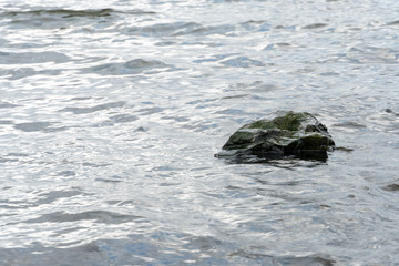 a protruding rock above the water. Raging surface of the sea with a lot of incoming waves on the rock.