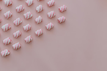 Marshmallows white and pink chewy candy lie over pink background, closeup.