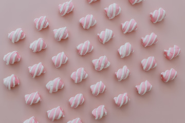 Marshmallows white and pink chewy candy lie over pink background, closeup.