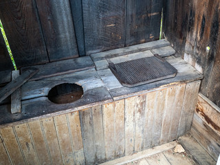 Abandoned two-seater outhouse in woods with lid.