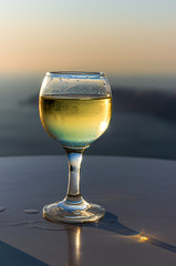 A glass of white wine against the background of a Santorini sunset