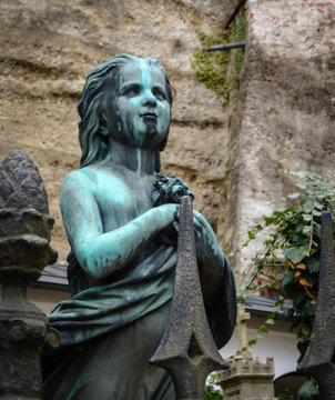 Old bronze statue of young girl at St Peters cemetery in Salzburg Austria