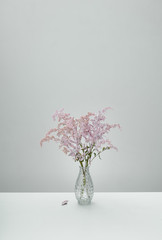 Delicate pink flowers in a glass vase on a blue background