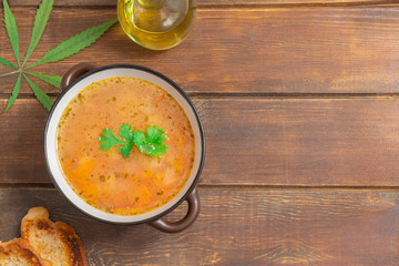 Top view of vegetable cannabis soup in a bowl on wooden background with copy space