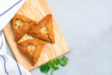 Top view of freshly baked pastry Ocpocmaq, Bashkirs and Tatar national dish on wooden board on neutral background, copy space © Elena