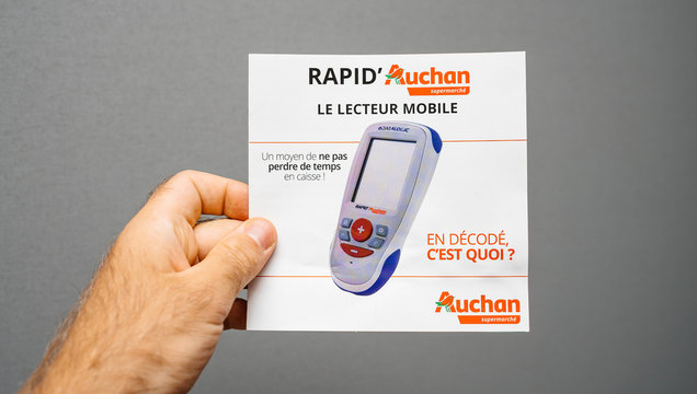 Paris, France - Sep 8, 2018: Man hand holding a Rapid Auchan Le Lecteur Mobile mobile reader of products to scan groceries