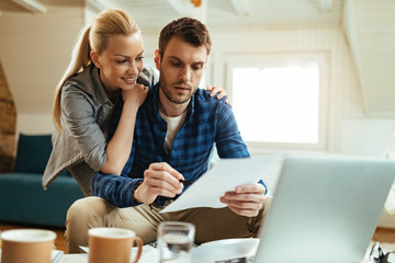Happy couple talking about their home budget while analyzing their finances at home.