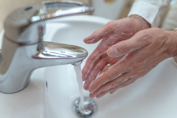 businessman in a white shirt washes his hands with soap in the sink