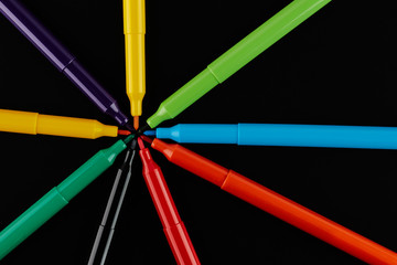 Fototapeta premium Colored markers isolated on a black background, top view