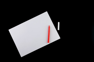 Blank white sheet with a red marker on a black background, top view