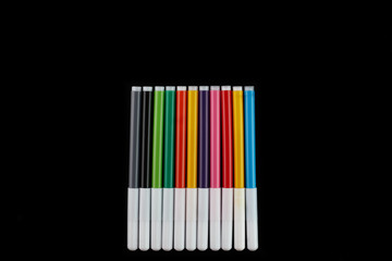 Colored markers isolated on a black background, top view