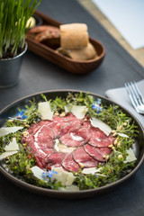 Carpaccio thin sliced beef meat with cheese, herbs