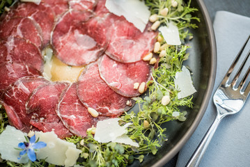 Carpaccio thin sliced beef meat with cheese, herbs