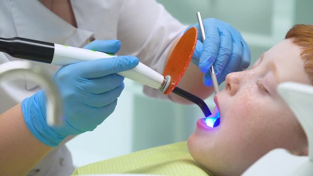 Female dentist in work. Little boy at reception at dentist in dental chair. Pediatric dentistry