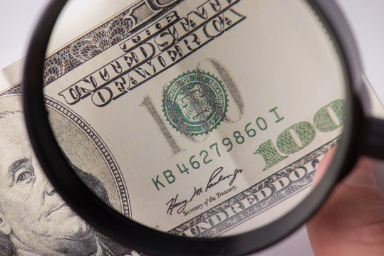 Fake money concept. Cropped close up photo of human finding false cash looking through magnifying glass - Powered by Adobe