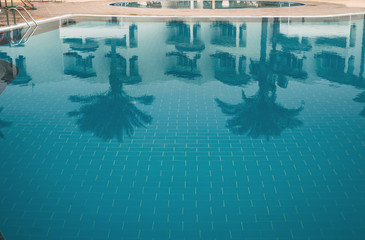 Reflection of palm trees and buildings in the pool water. Holidays at sea with palm trees. Luxury resort on the Red Sea, hotel and swimming pool, typical Arabic architecture