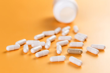 Opposition. A lot of white pills and one brown on a yellow background. The problem of choice and efficiency. Health and medicine.