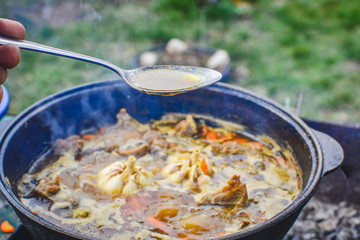 Pilaf on the cooking stage, zirvak with garlic, raisins, carrots, onions, lamb, barberry, saffron, zira and oil in a cauldron, boiling on the fire